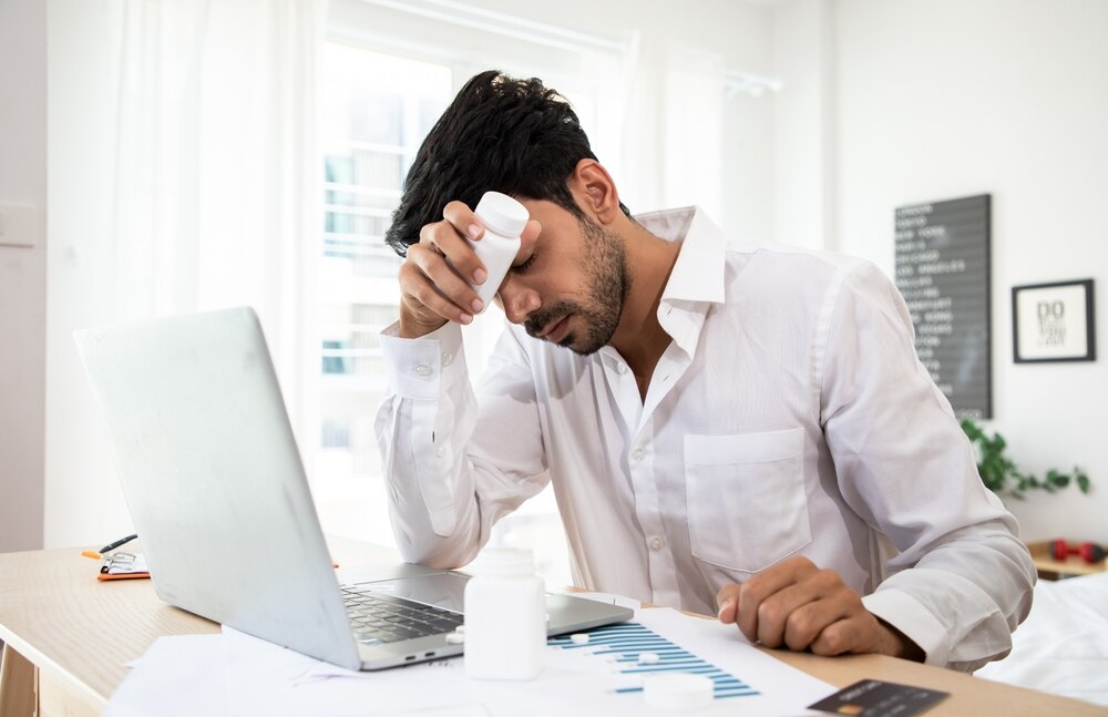 An upset man holding pills. 