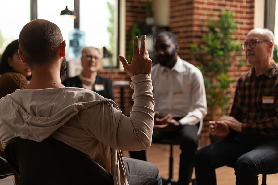 A man raises his hand in an alcohol support group.