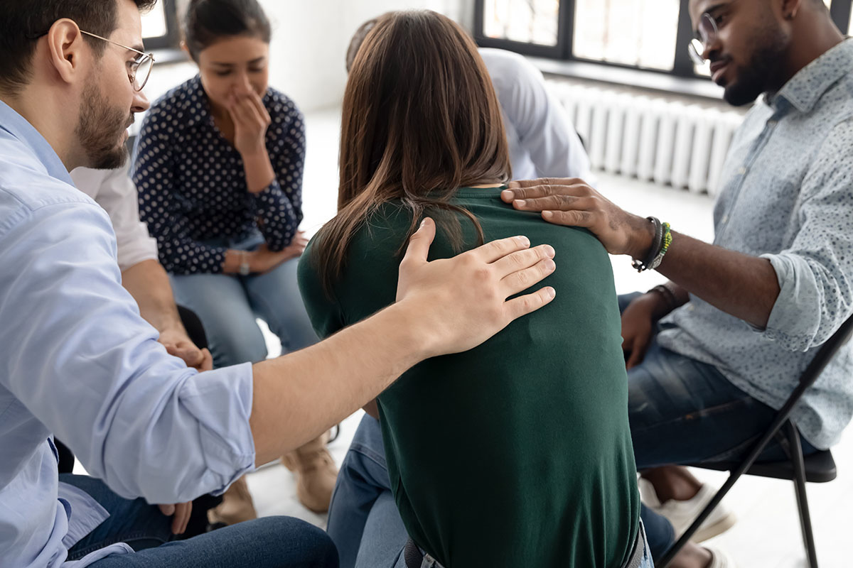 People comforting a woman in a group therapy session.