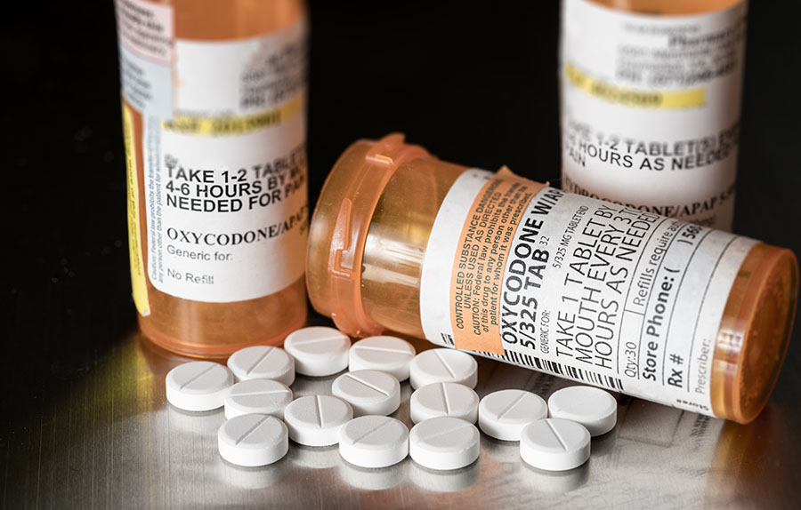 Several bottles of prescription opioids displayed against a black background.