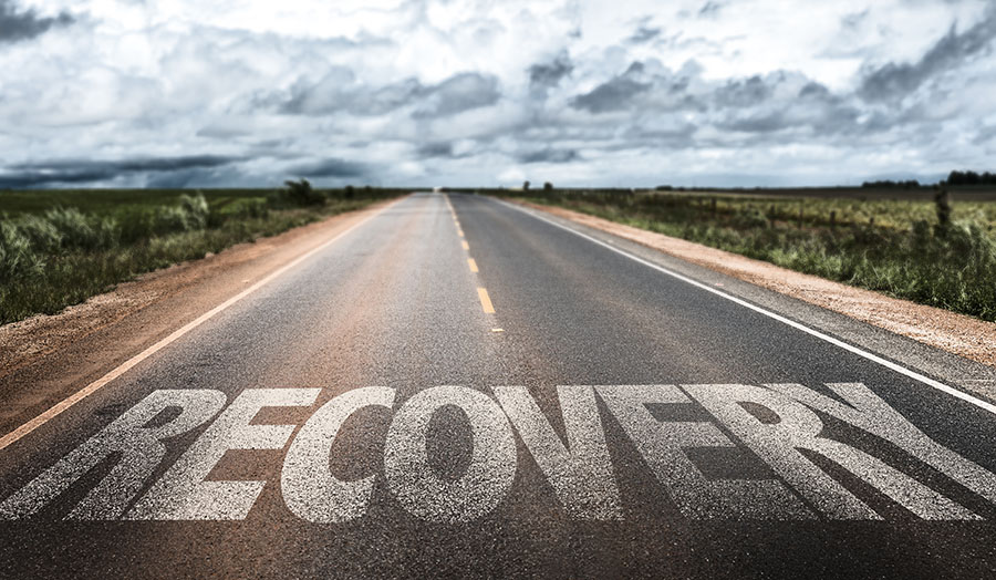 The word “recovery” is written on a road, indicating the beginning of the path to recovery.