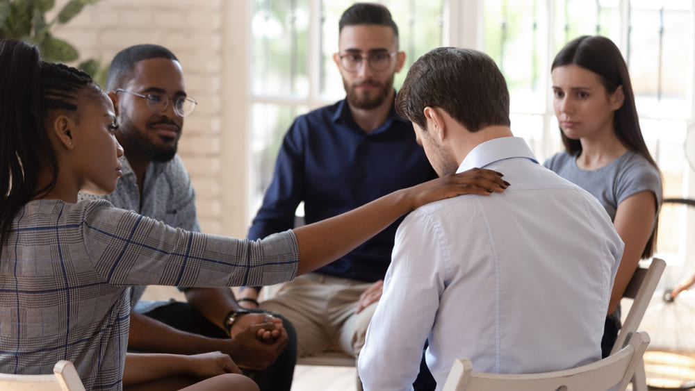A support group comforting a man. 