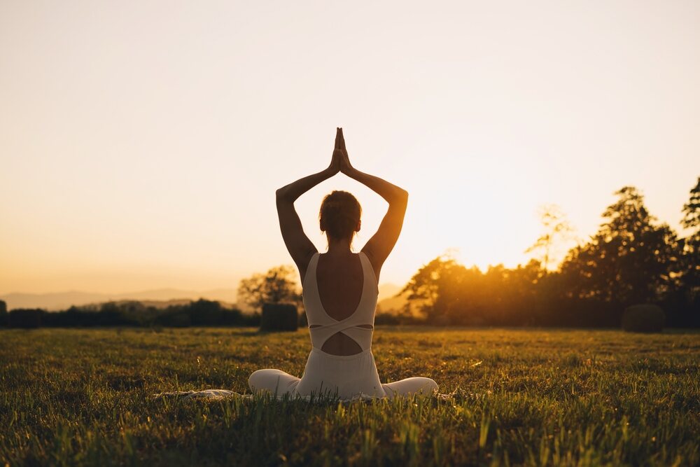 A person doing yoga in a field at sunset