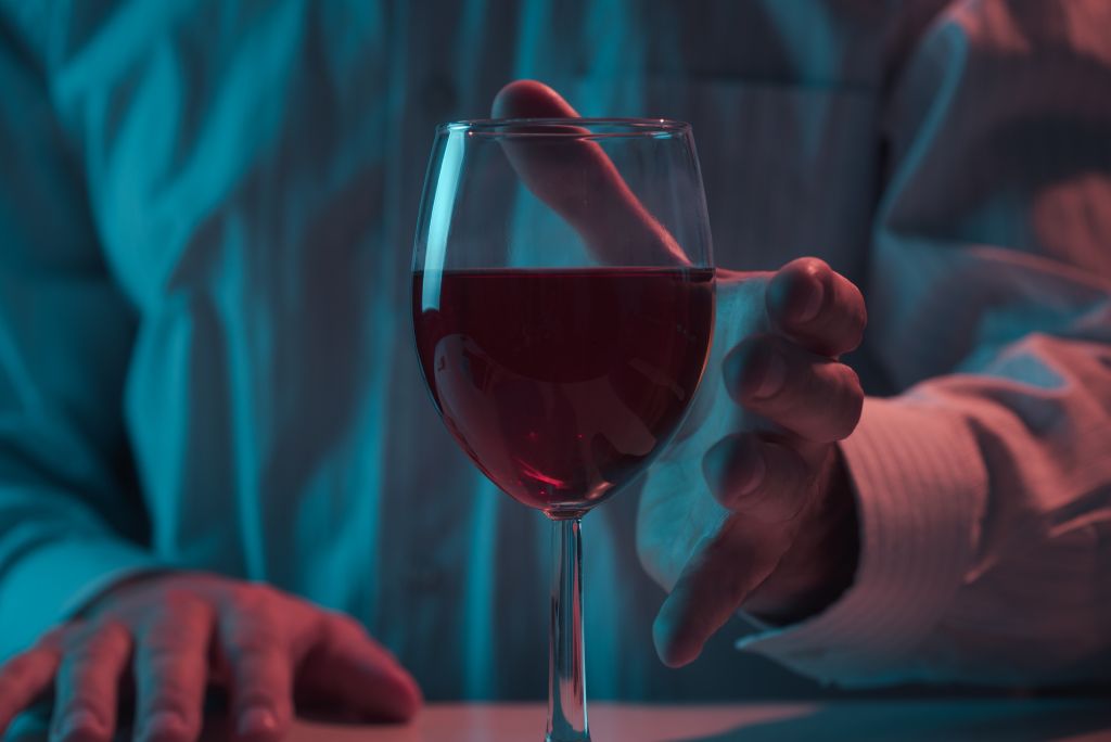 A person reaching for a glass of wine