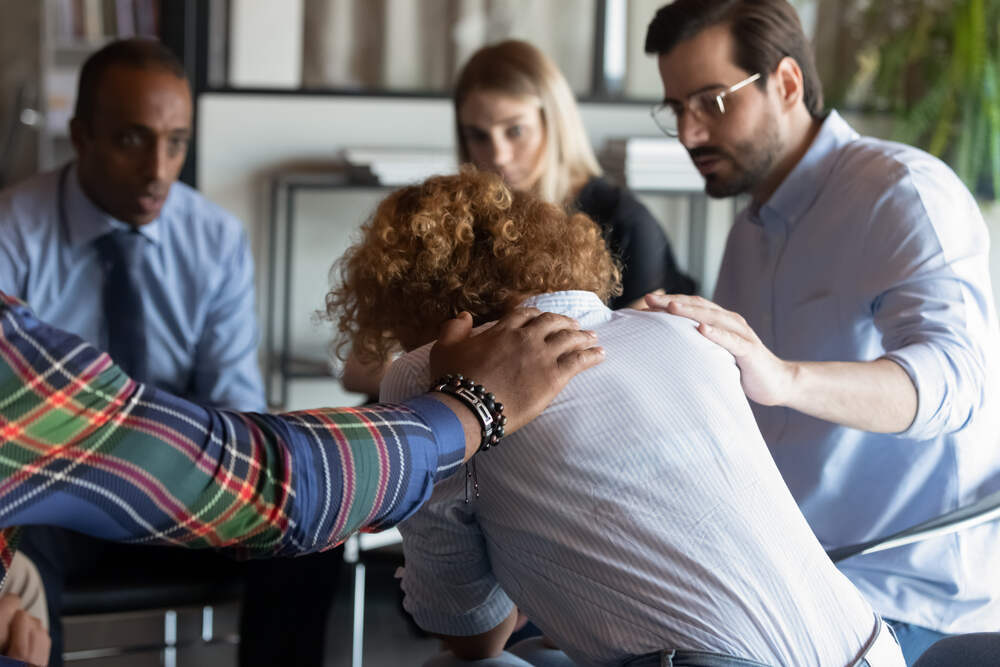 A person in group therapy being comforted